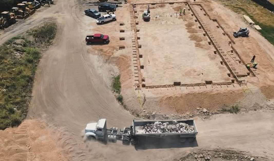 Aerial view of a dump truck hauling crushed material to a foundation pad on a Houston-area build
