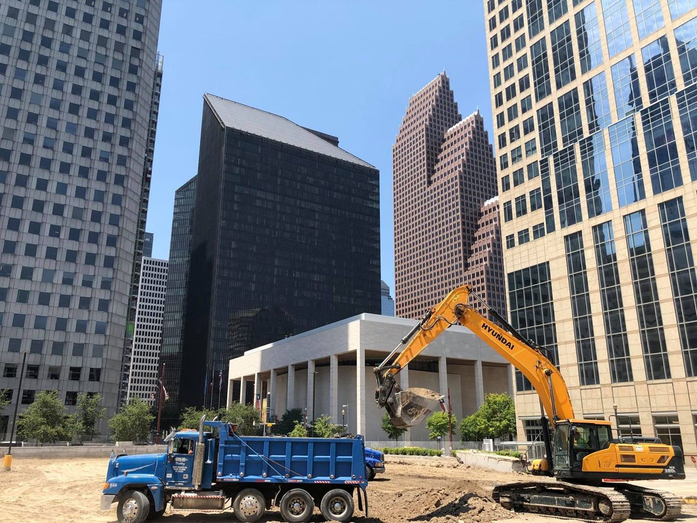 Dump truck and excavator on a downtown Houston site work project beneath the skyline