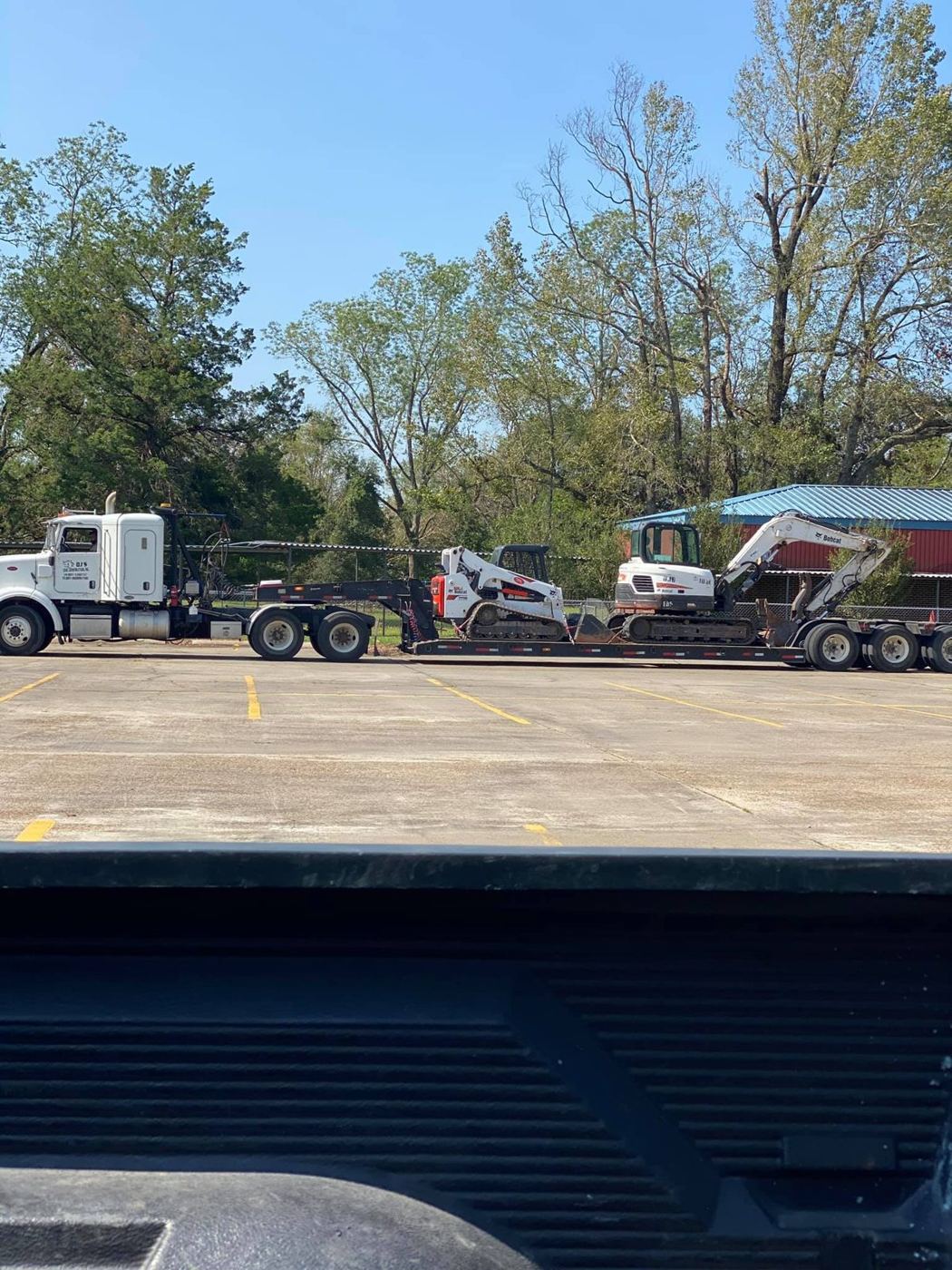 Supreme Logistics lowboy transporting a skid steer and mini excavator to a jobsite